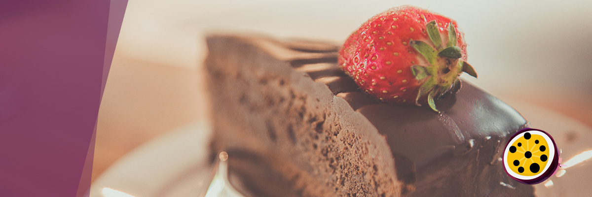 There is a chocolate cake on a white plate. It has strawberry on top of it