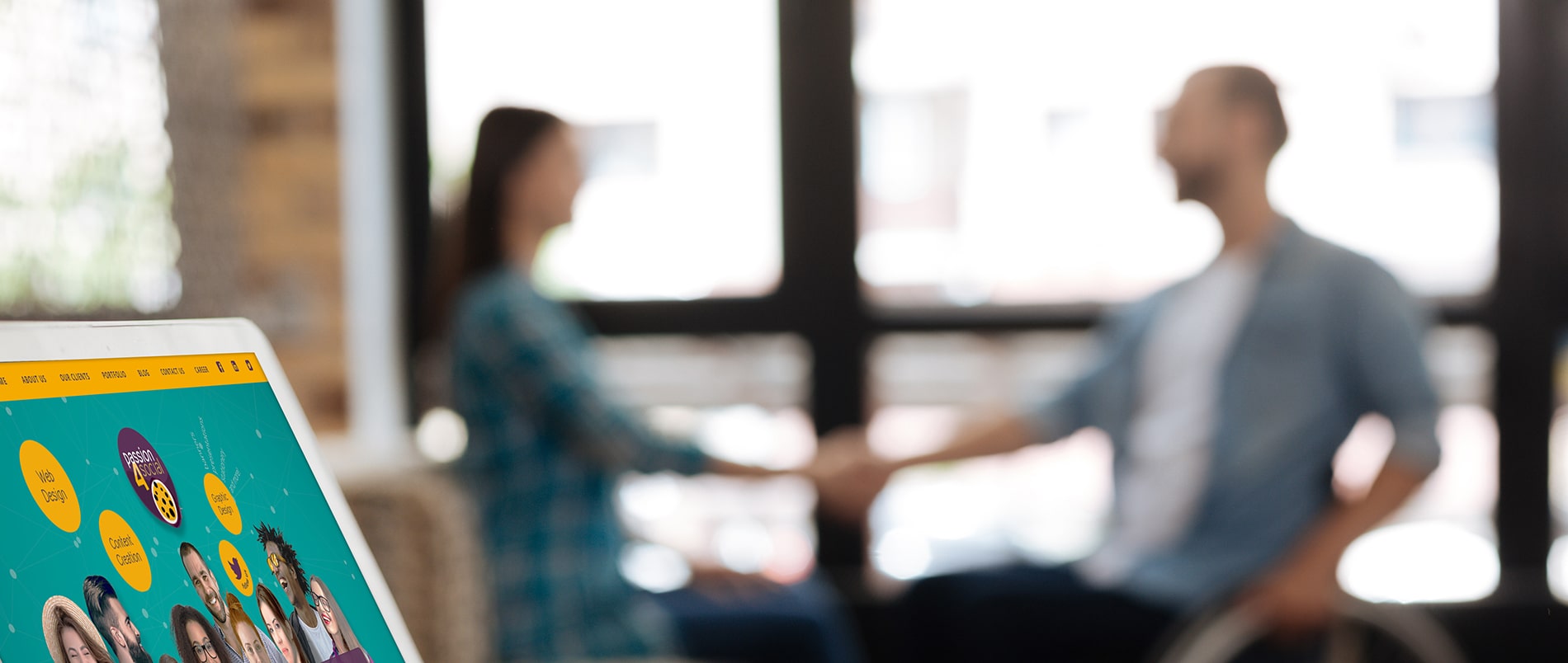 At the foreground there is a laptop with passion 4 social website. In the background there is a blurred picture of a man and a woman sitting at the table and having a conversation
