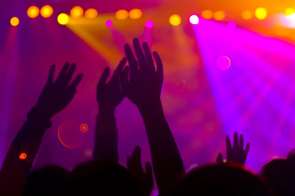 purple nightclub lights with hands in the air from the crowd