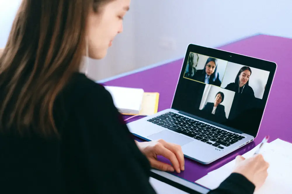 woman on a video call with 3 people at a purple desk