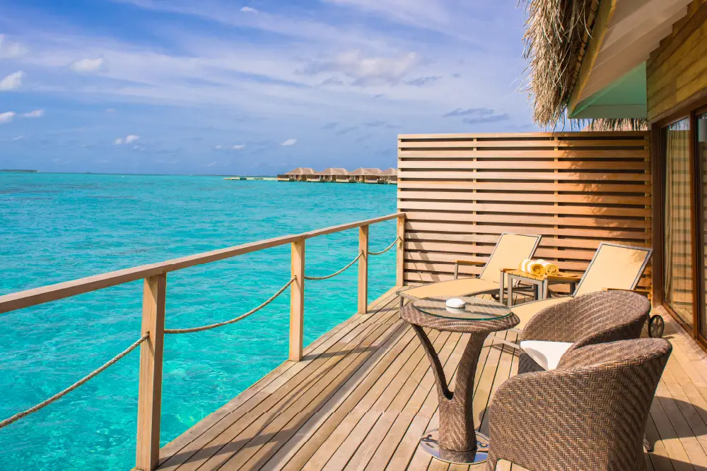 wooden chairs and table on a balcony facing clear blue sea and sky