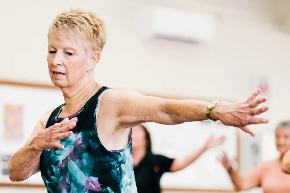 An older woman is wearing a sports top and doing exercises