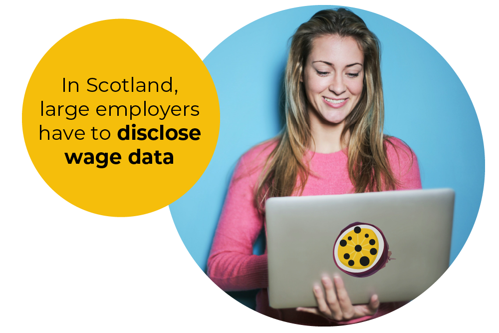 A woman wearing a pink top looking at her laptop and smiling and to her left is a heading that says in Scotland large employers have to disclose wage data.