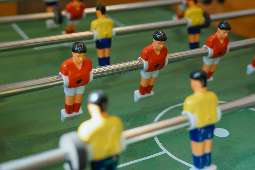 A close-up of a foosball table with players in red and yellow jerseys