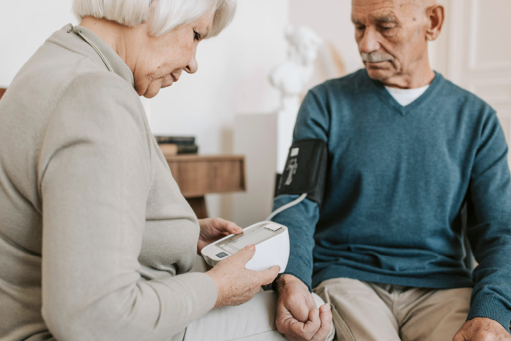 An older woman measuring blood pressure for an older man