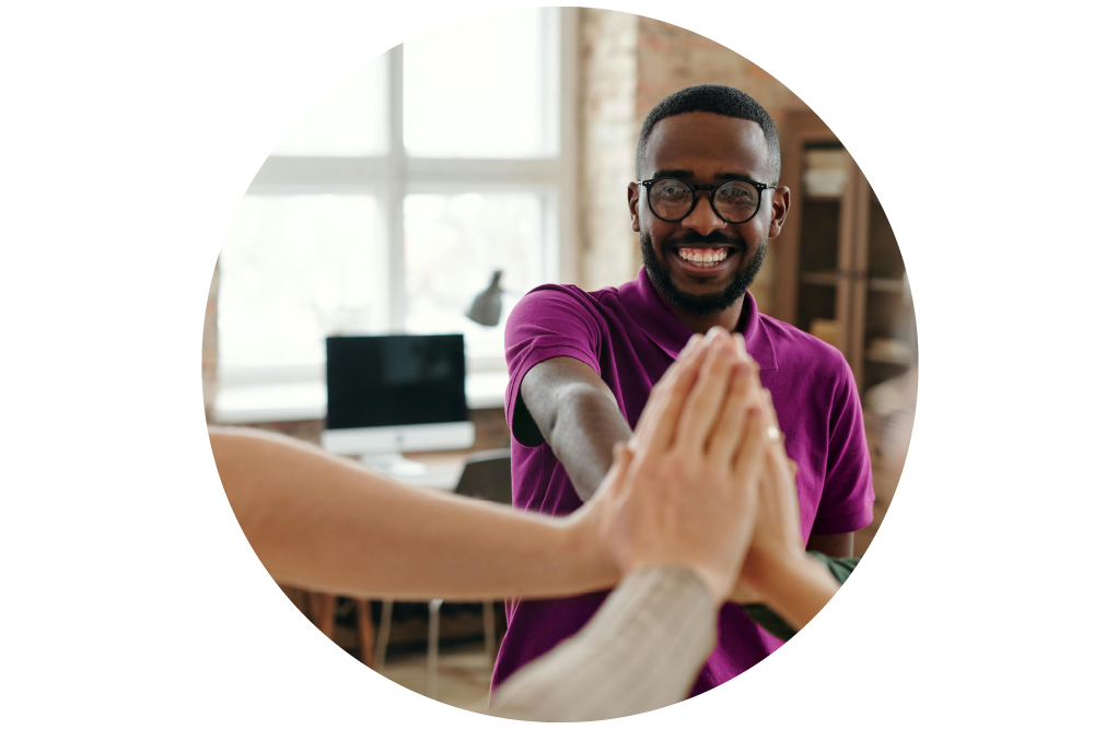 A man giving a high-five to 3 other colleagues in a modern office setting