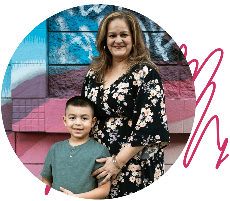 A woman in a black dress with a floral pattern is standing beside her son, who is wearing a green shirt