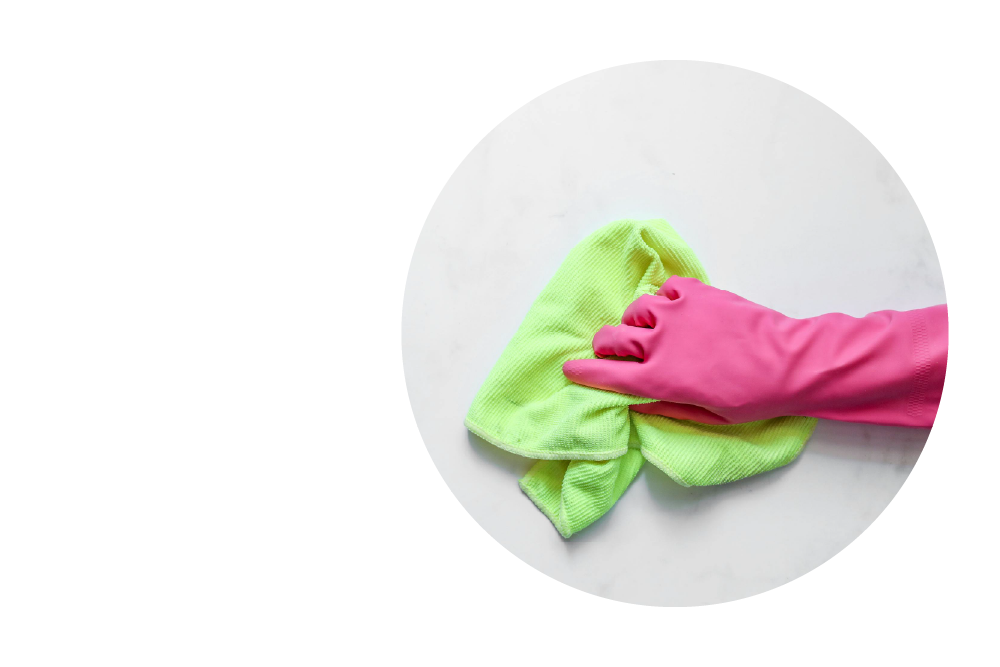 A hand wearing a bright pink rubber glove is wiping a surface with a neon green microfiber cloth.