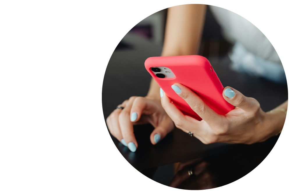 a close-up image of hands with pale turquoise nail polish holding a mobile phone with a red protective cover.