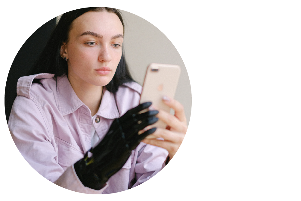 a person with a prosthetic hand holding up a mobile phone, looking as if deep in concentration.