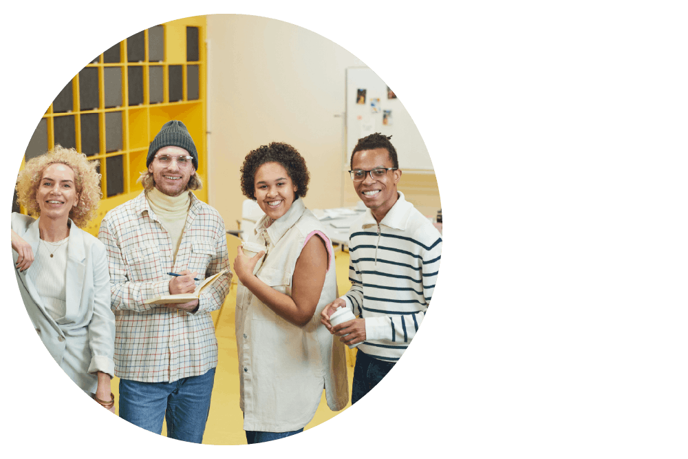 four people standing in a row, holding notebooks and takeaway coffee cups and smiling widely for the camera.