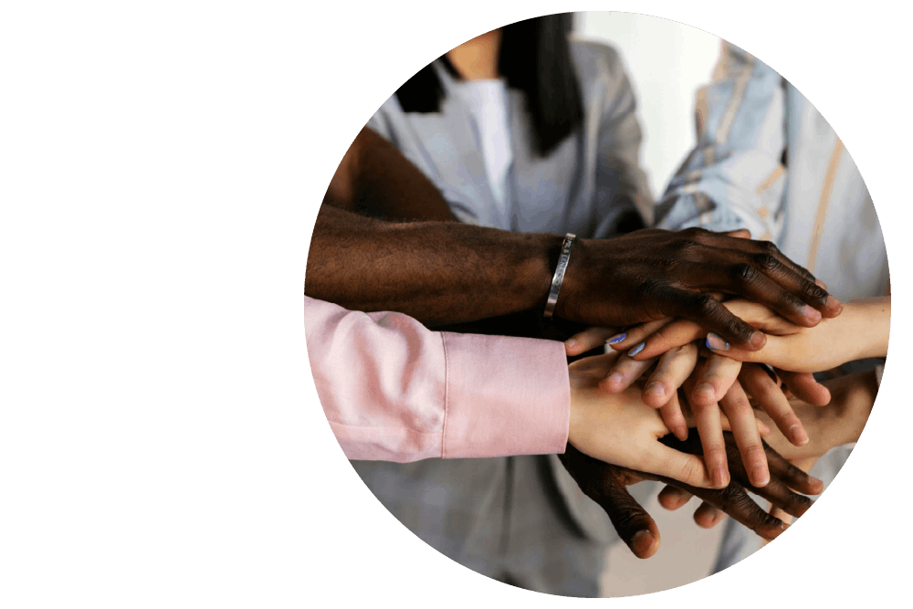four people’s outstretched hands stacked together in unity, with varying skin tones