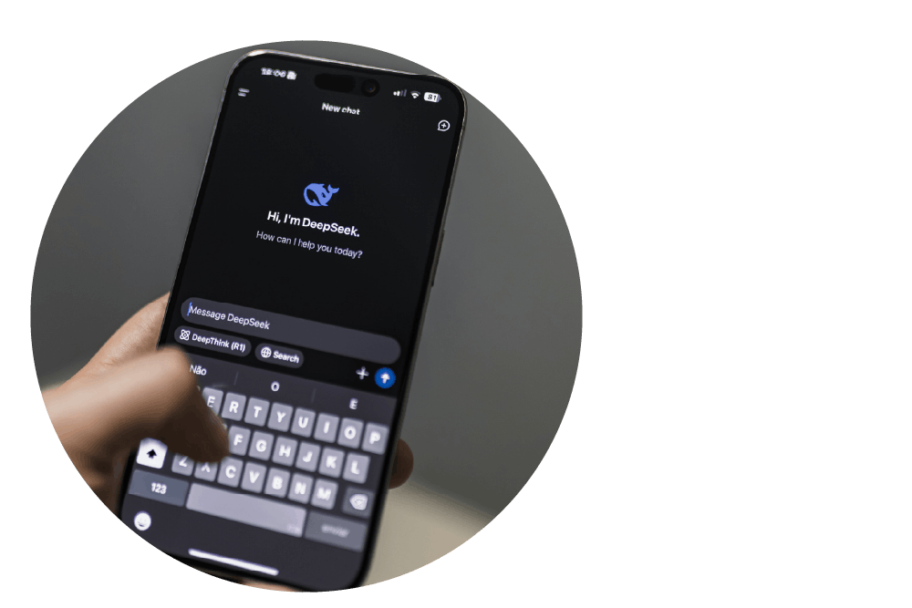 a close-up view of a hand holding a mobile phone. The screen displays the DeepSeek AI interface and keyboard, with a thumb hovering over the keys.