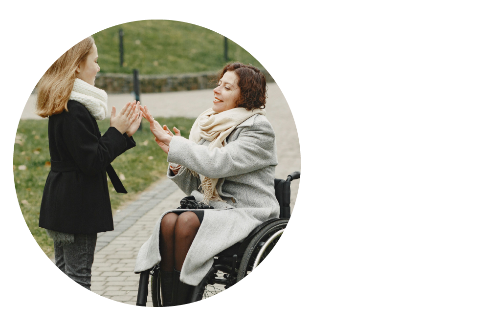 Aligned to the left, a circle frames an image of a woman who is a wheelchair user happily playing a hand-clapping game outdoors with a female child