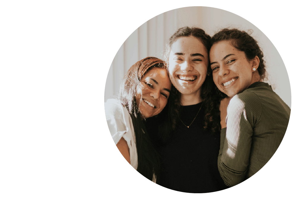 three people embracing each other and smiling widely.