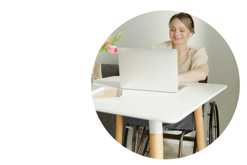 a person using a wheelchair working at a desk using an open laptop computer.