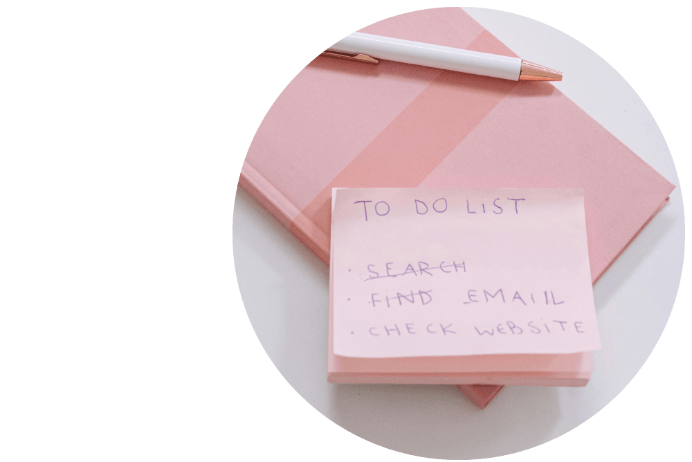 A stack of sticky notes on top of a notepad and pen against a white surface. The sticky note reads: ‘To-do list.’
