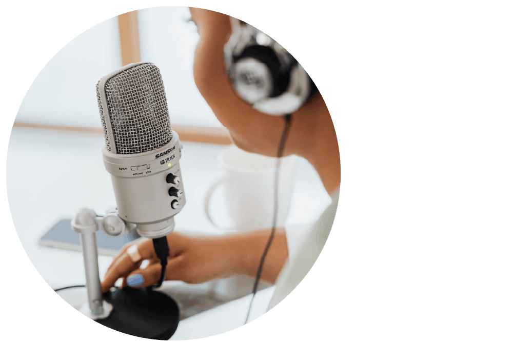 A studio microphone with a person wearing headphones recording a podcast