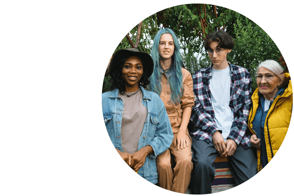 A diverse group of people posing side by side for the camera with trees in the background.